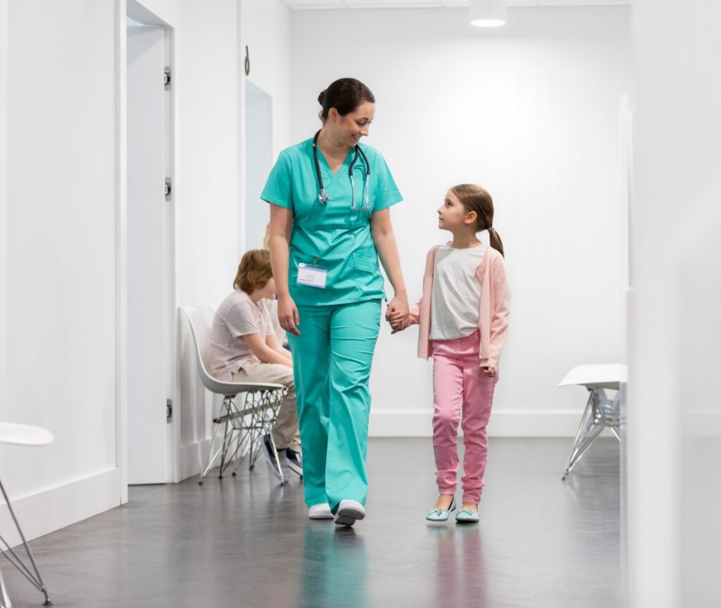 Female doctor and young girl walking in corridor of a children's Hospital.